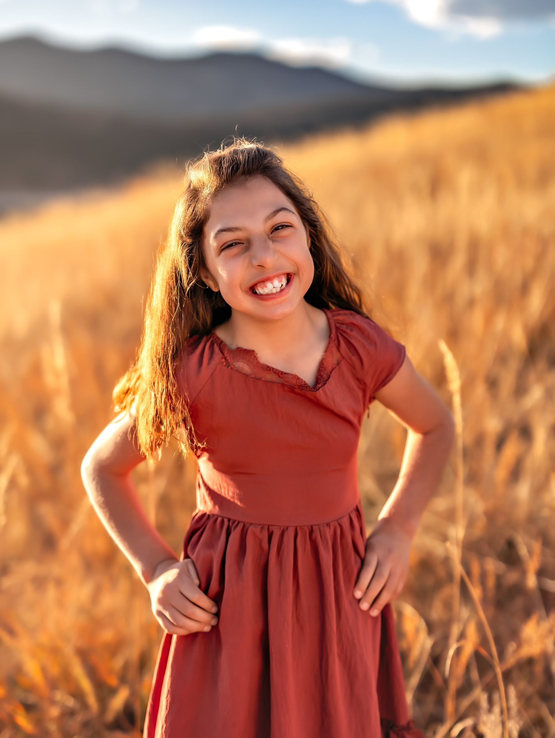 Harper in a red dress and standing in a field and smiling