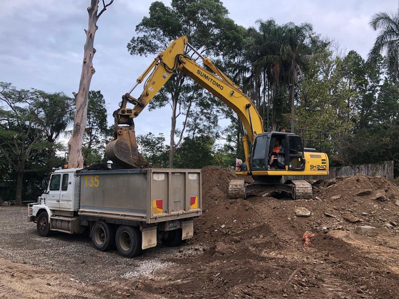 A yellow excavator is loading dirt into a dump truck.