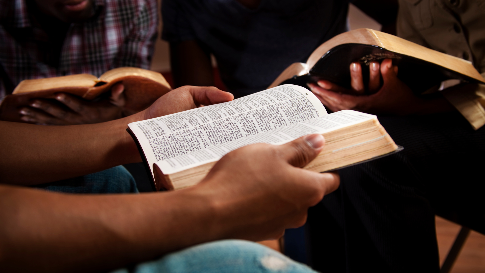 A group of people are sitting in a circle reading the bible.