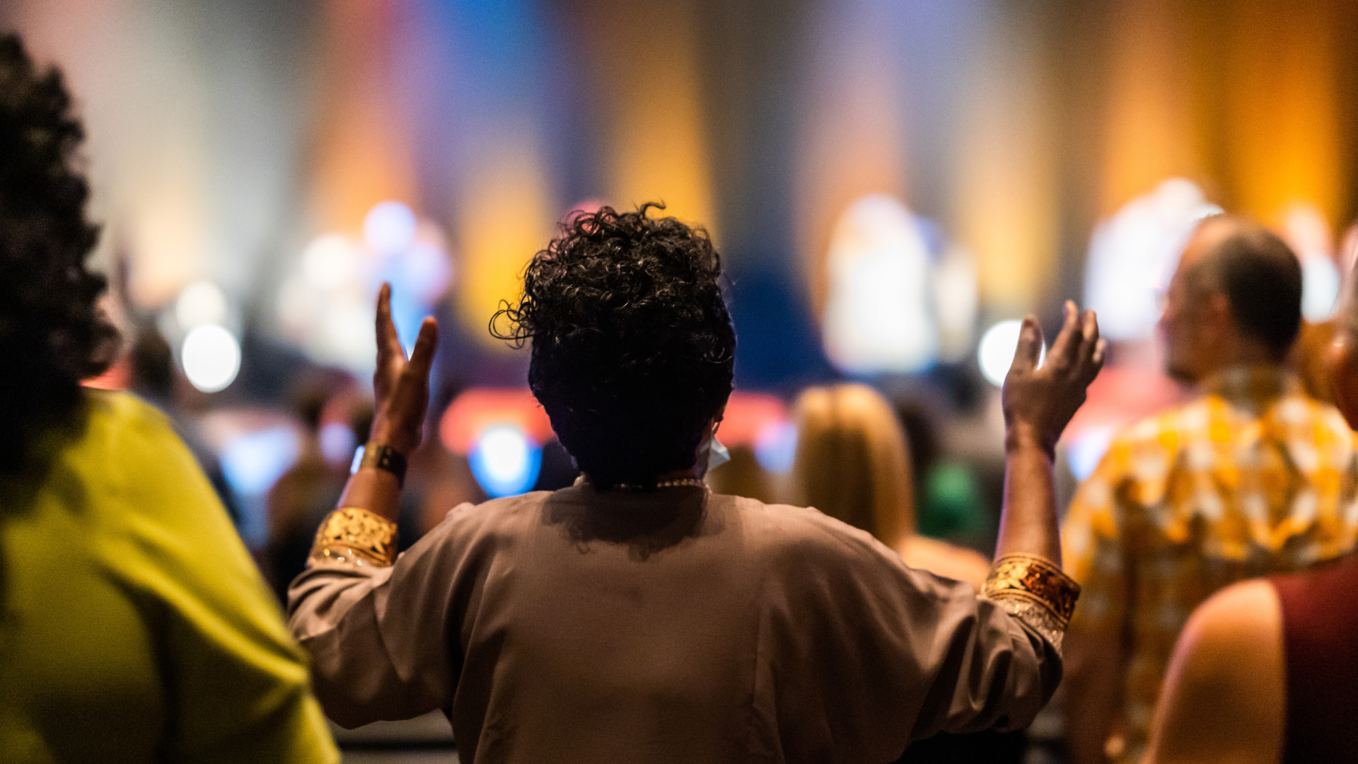 A woman is standing in front of a crowd with her hands in the air.