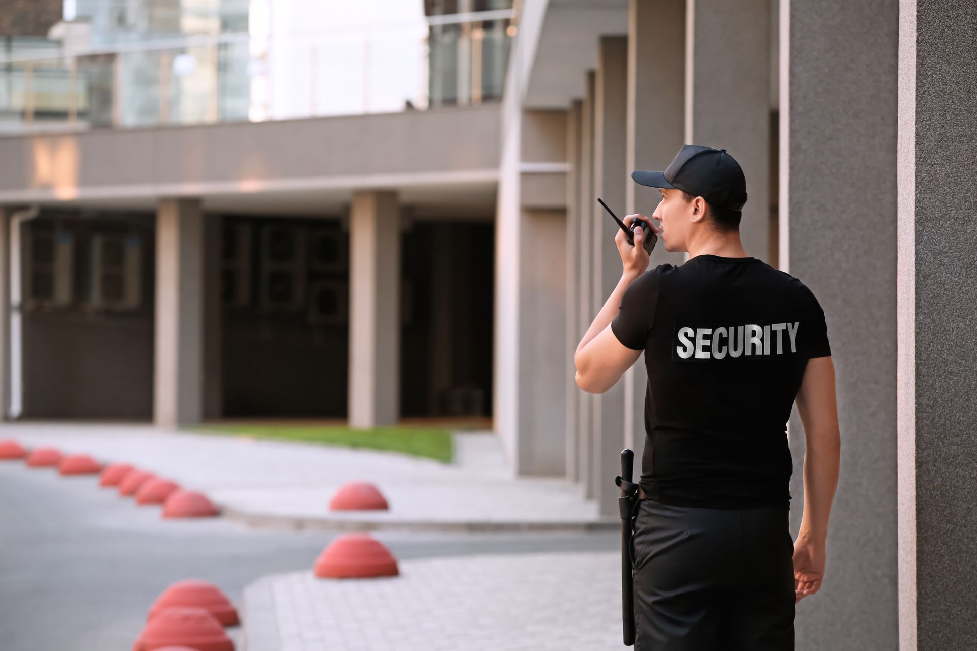 Security services guard patrolling building exterior with radio.