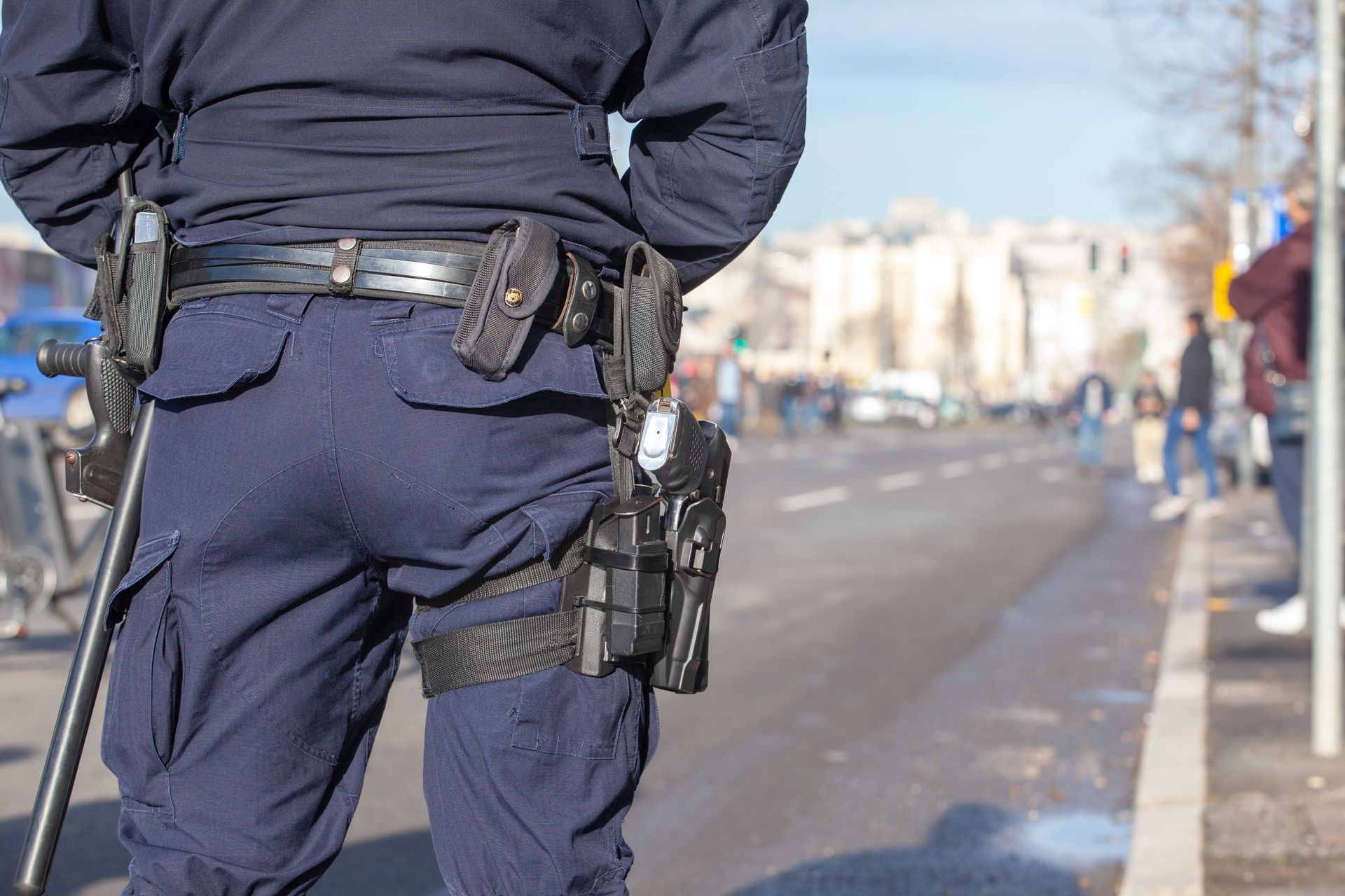 A security guard standing on a street with equipment visible.