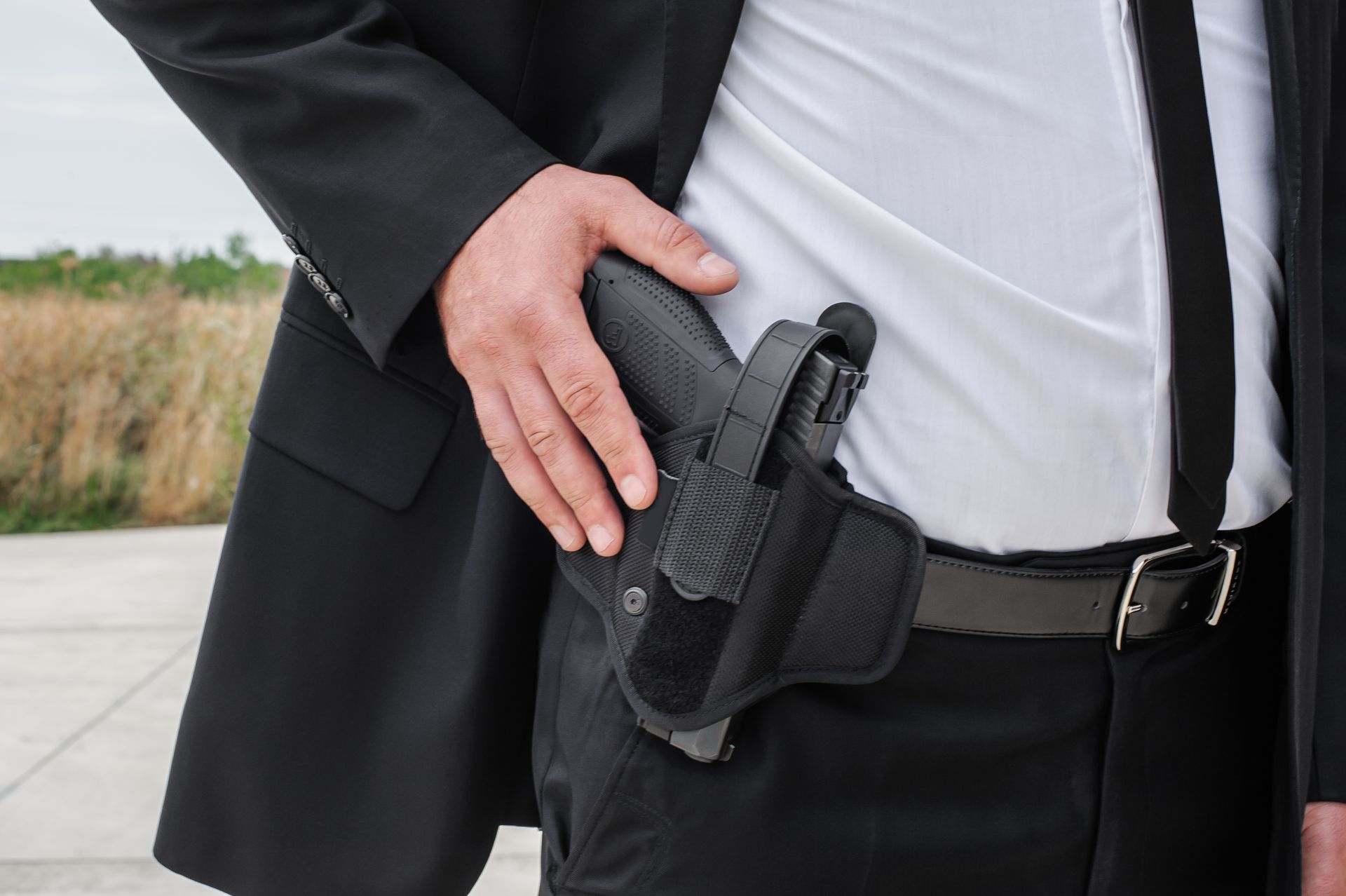 Close-up detail view of male residential security guard hand with gun in bandolier belt. Close-up detail view of male residential security guard hand with gun in bandolier belt.