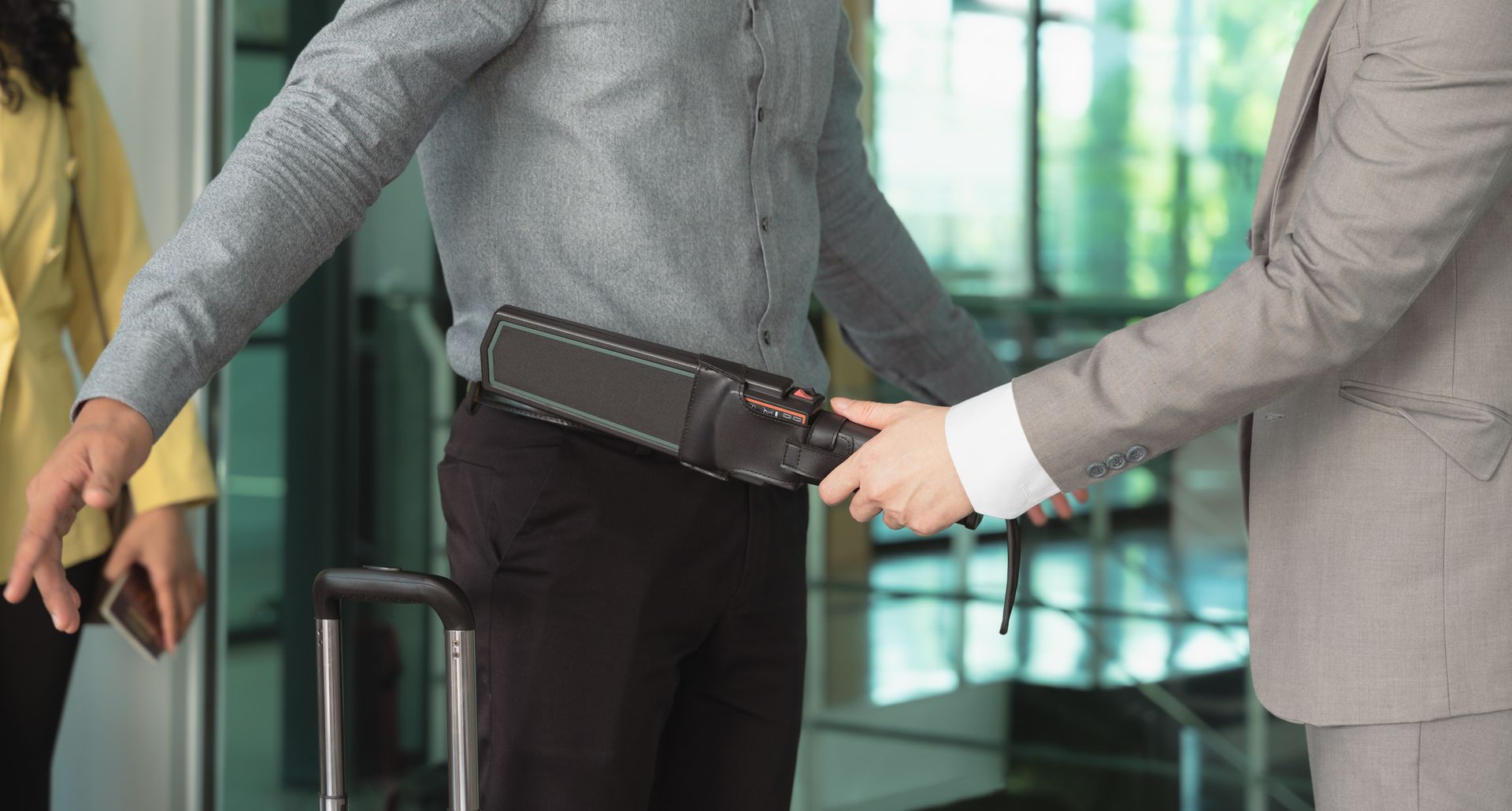 Security officer using a metal detector on a male client at commercial building entrance.