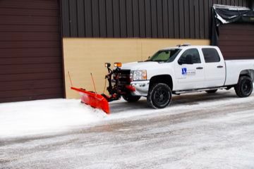 White pickup truck with a red snowplow clearing snow.
