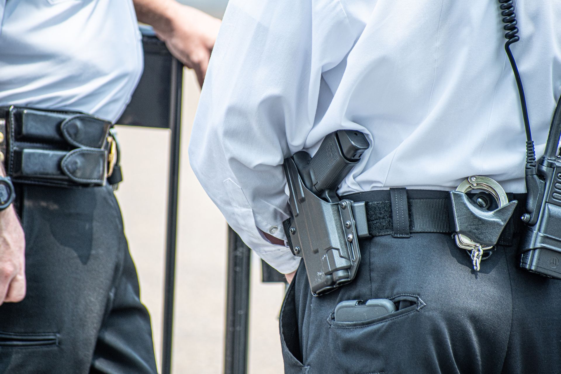 Two male professional armed security guards outside a property.