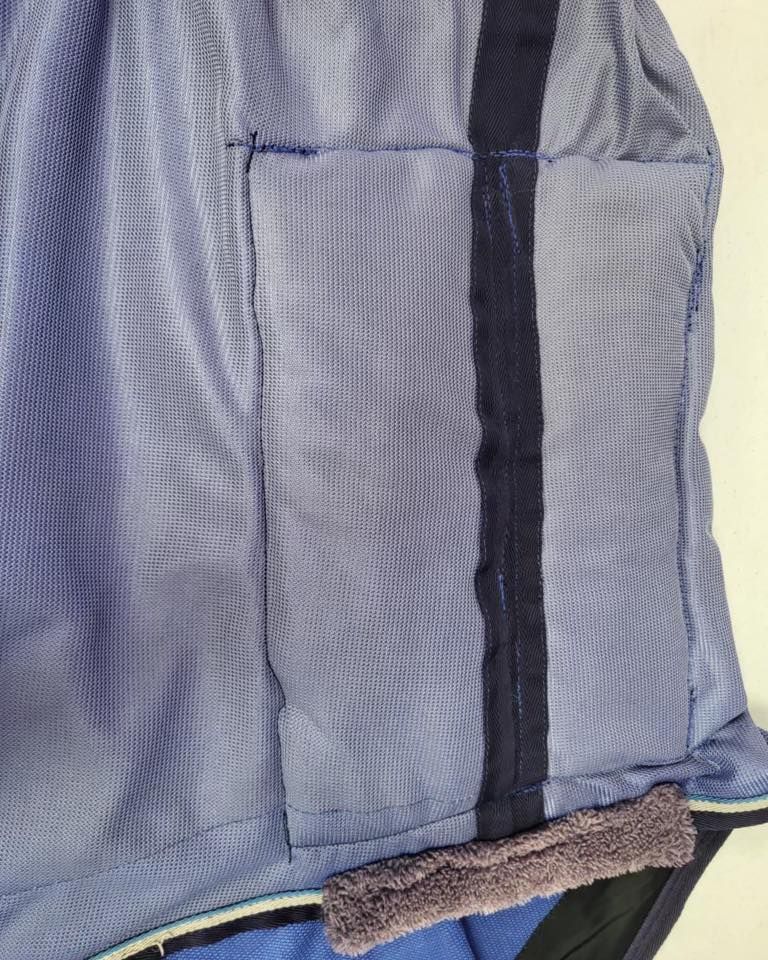 Blue mesh horse blanket detail, with dark blue vertical stripe and belly band with fur.