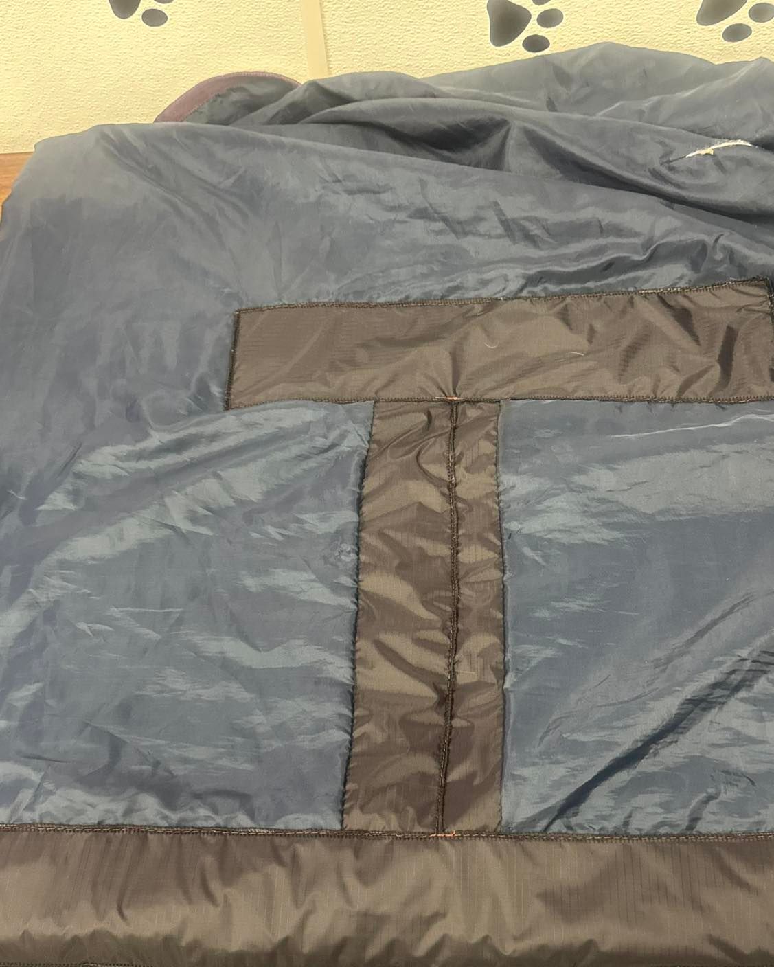 Blue and black sleeping bag interior with reinforced, quilted center seam.