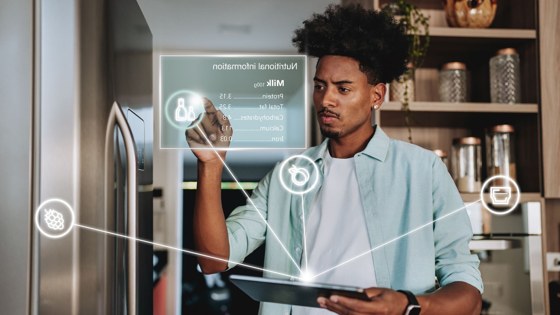 Man using tablet interacting with a smart refrigerator interface in a kitchen, looking focused.