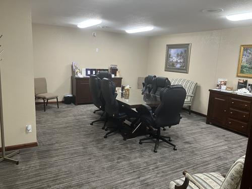 Conference room with long table, black chairs, artwork, and beige walls.