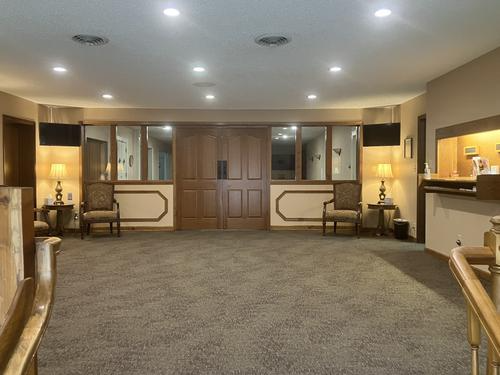 Lobby with carpet, wooden doors, seating, lamps, and a reception desk.