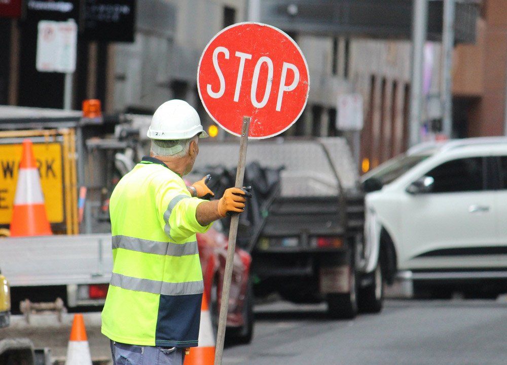 Older Man With A Stop Sign Directing The Traffic — Diamond Traffic Designs In Alice Springs NT