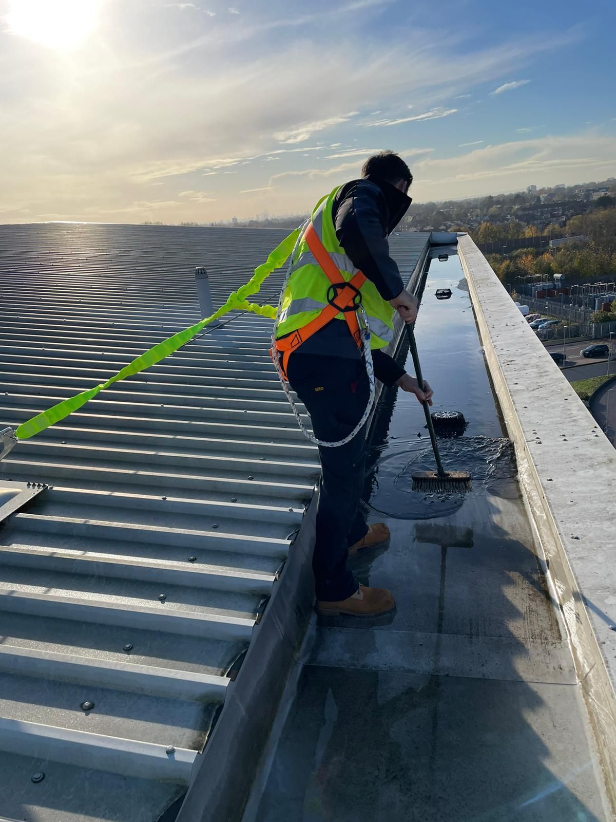 A man is cleaning the roof of a building with a broom.