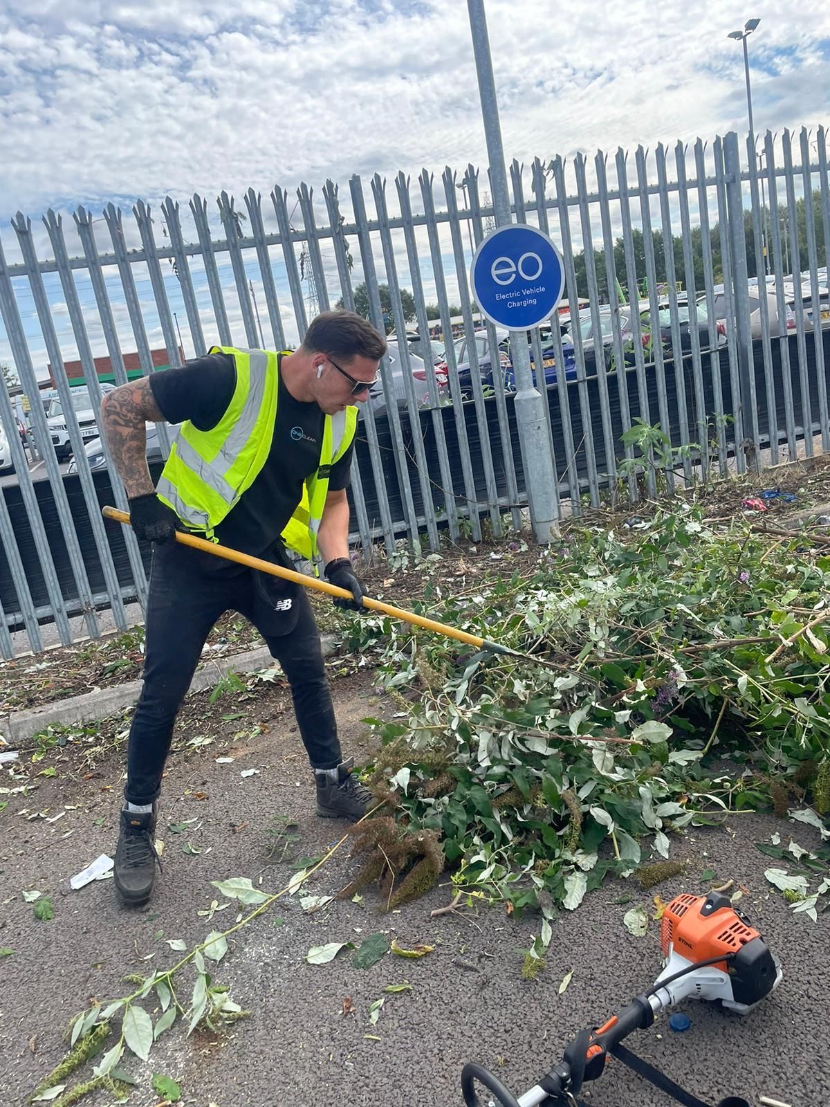 A man is standing next to a fence holding a broom.