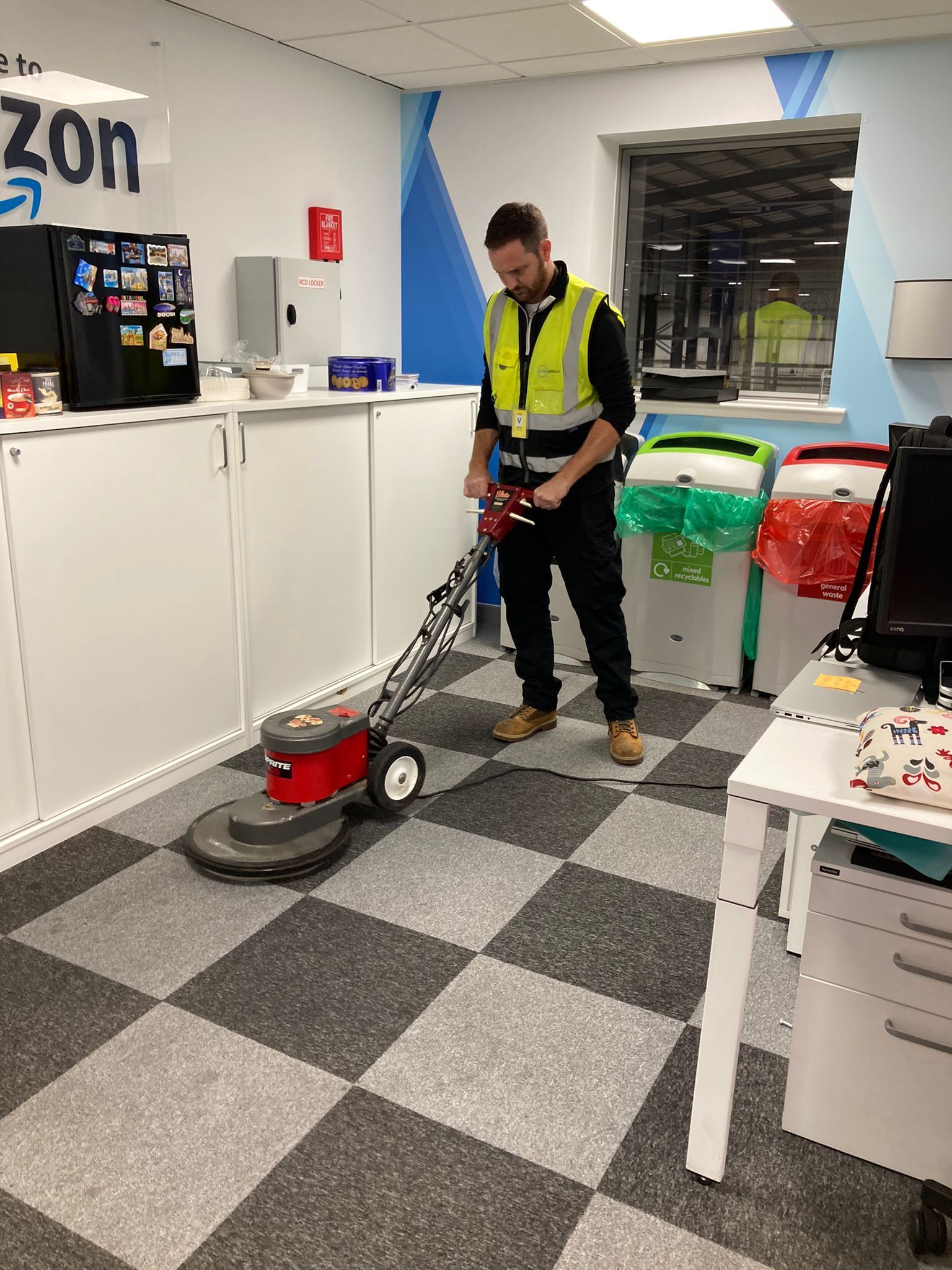 A man is cleaning the floor of an office with a machine.