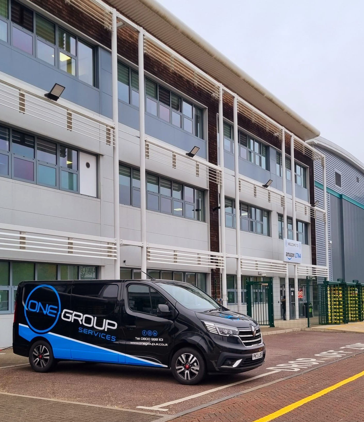A one group van is parked in front of a building