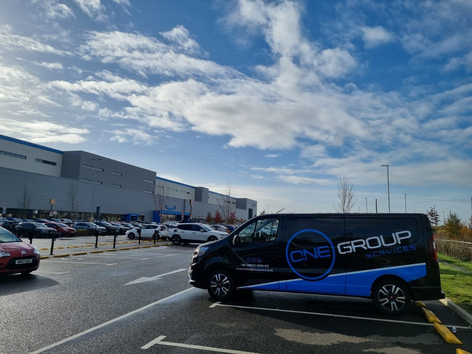 A van is parked in a parking lot in front of a large building.