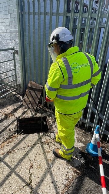 A man in a yellow safety vest is standing next to a fence.