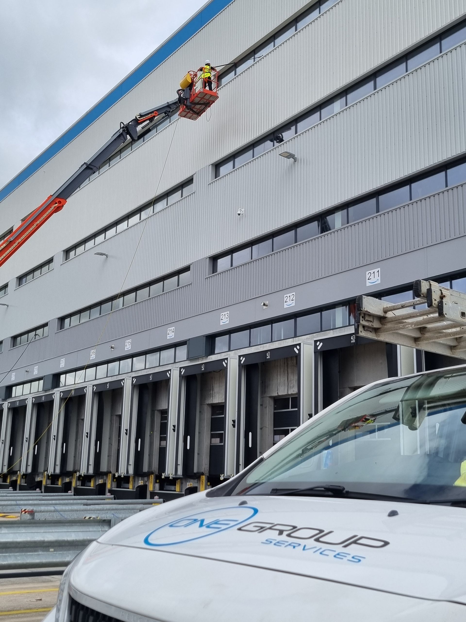 A white van is parked in front of a large building.