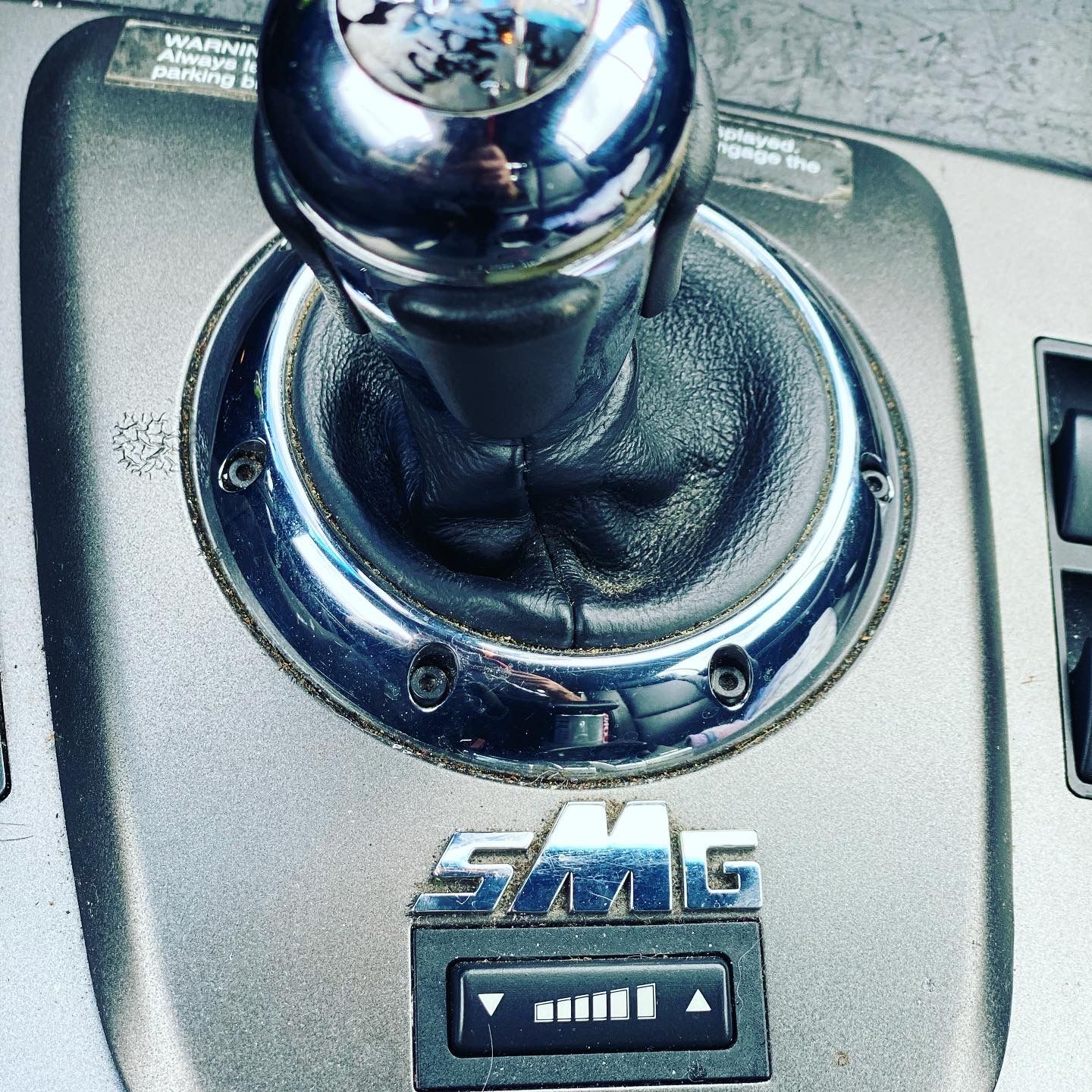 Car console with gear shift and SMG logo, featuring a mode selection button. | Velocity Motorwerks