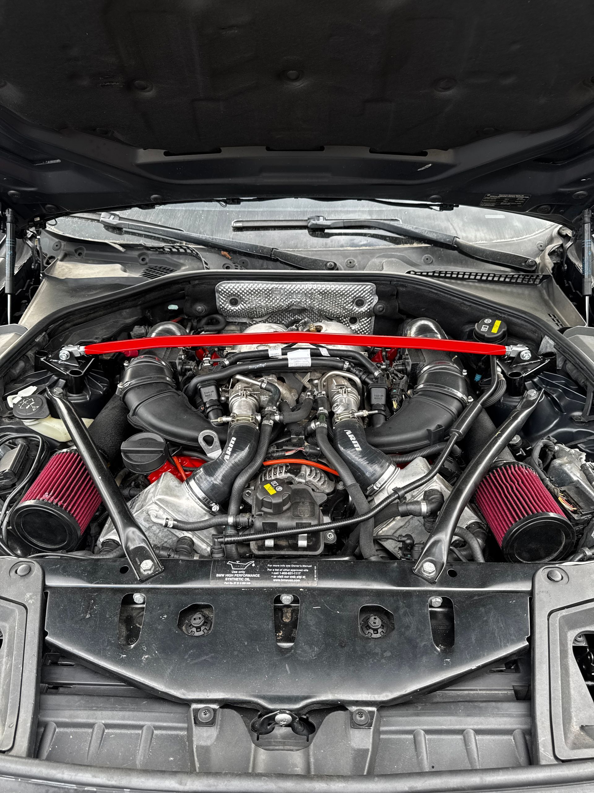 Car engine with red details, open hood. Black engine components with red air filters and bracing. | Velocity Motorwerks