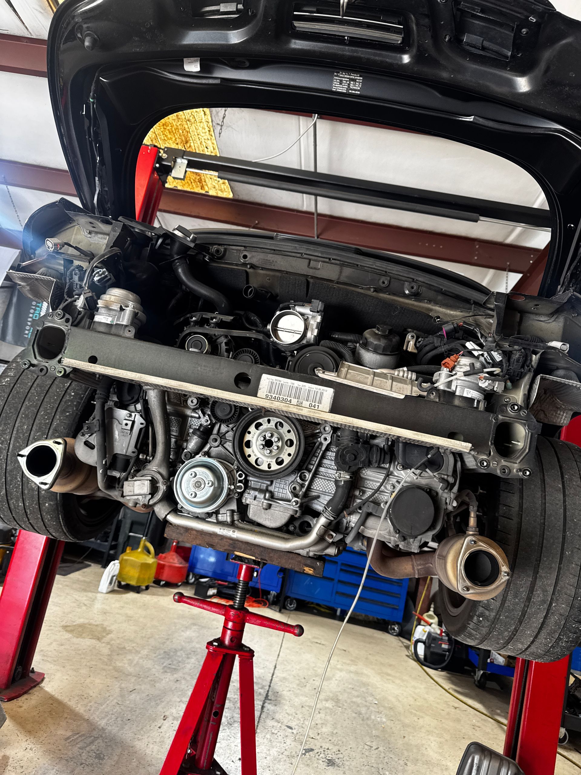 Car engine raised on a lift; various mechanical parts visible, with open hood. | Velocity Motorwerks