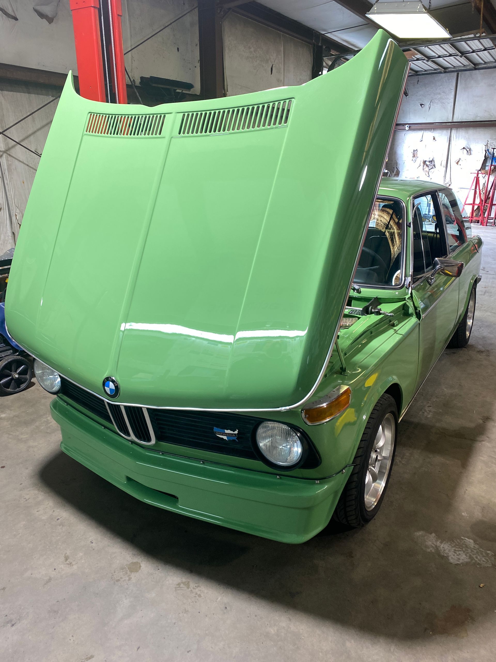 Green BMW 2002 with hood open in a garage. | Velocity Motorwerks