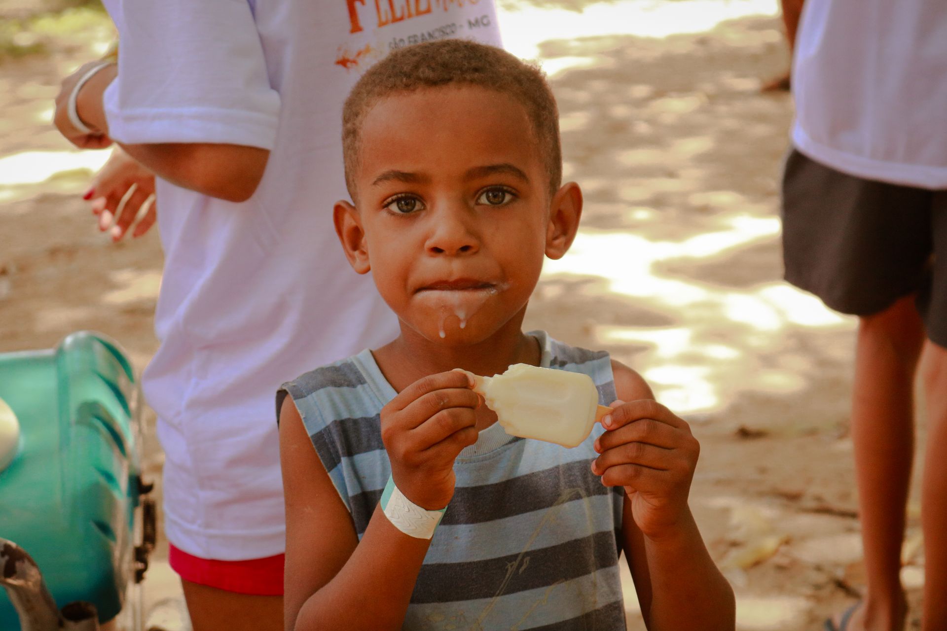 Um menino de camisa listrada está comendo um pedaço de comida.