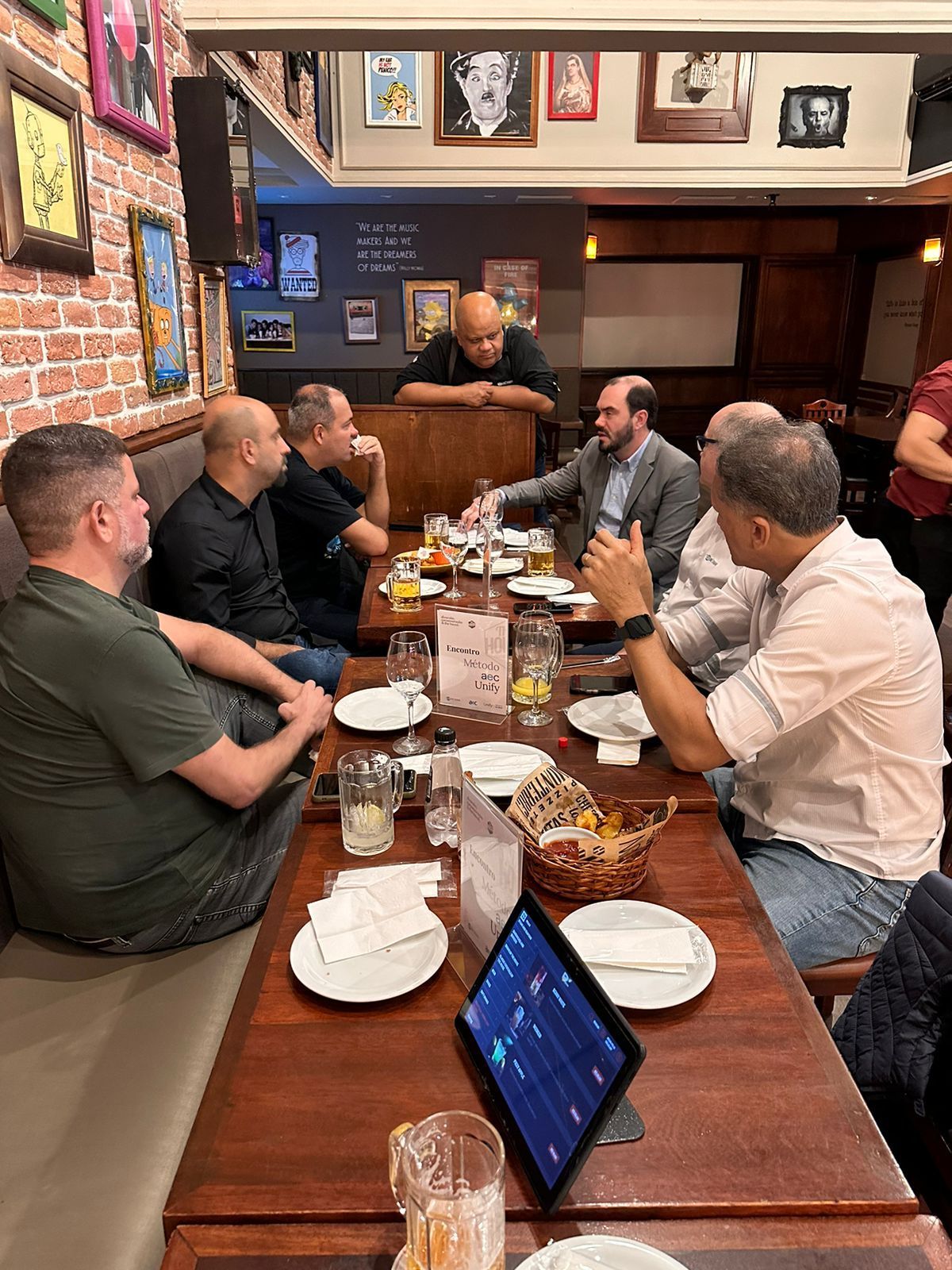 Um grupo de homens está sentado ao redor de uma mesa em um restaurante.