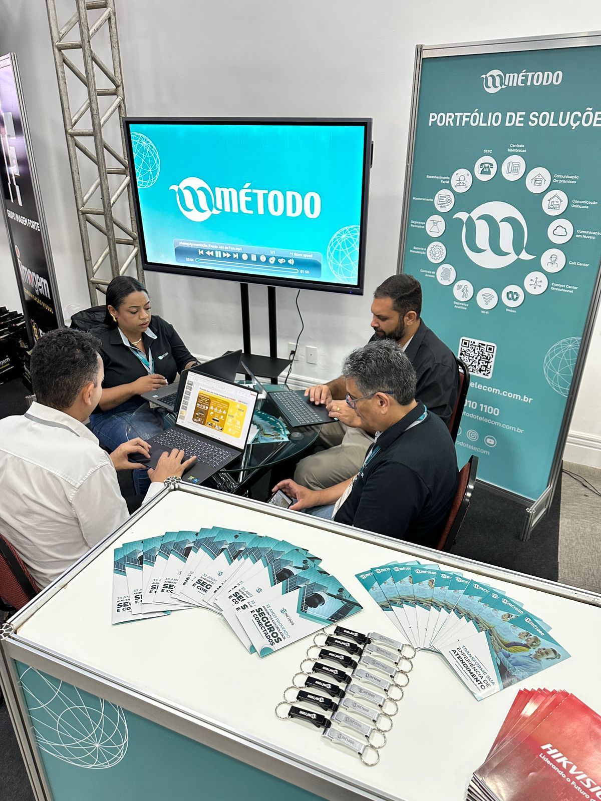 Um grupo de pessoas está sentado ao redor de uma mesa usando laptops.