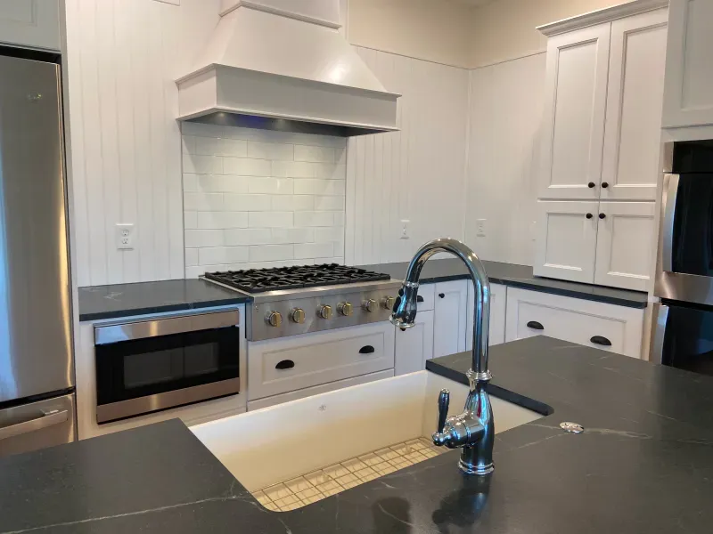 A kitchen with a sink , stove , microwave and refrigerator.