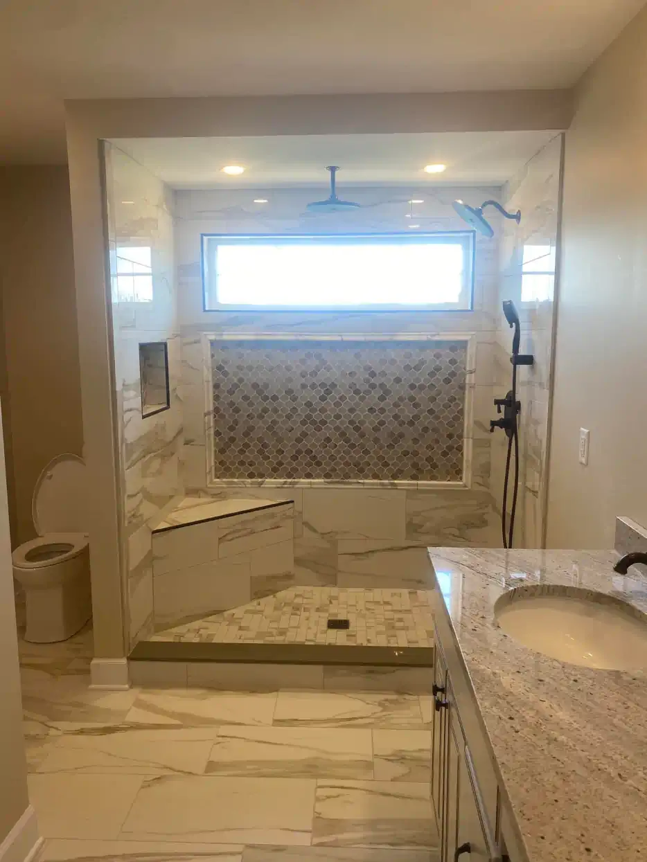 A bathroom with a walk in shower , sink , toilet and window.