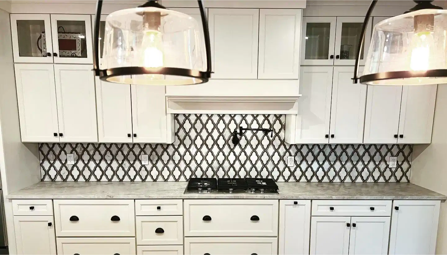 A kitchen with white cabinets , granite counter tops , and a stove top oven.