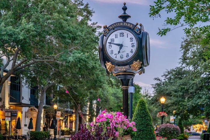 Town clock framed by historic Winter Park buildings.