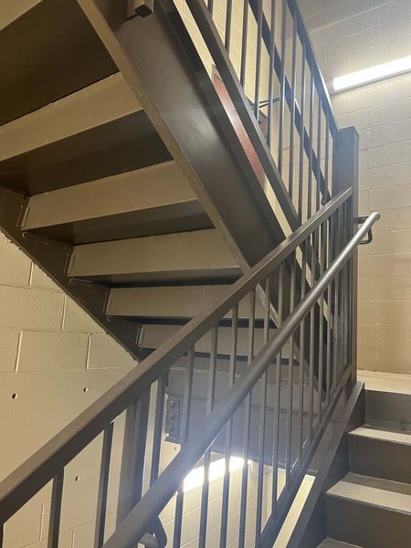 brown metal staircase in office stairwell with pipe railing