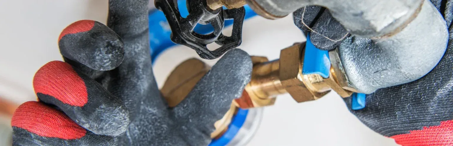 A close up of a person wearing gloves holding a valve.