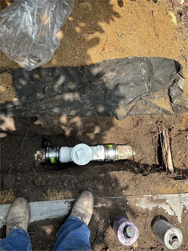 A person is standing next to a pipe in the dirt.