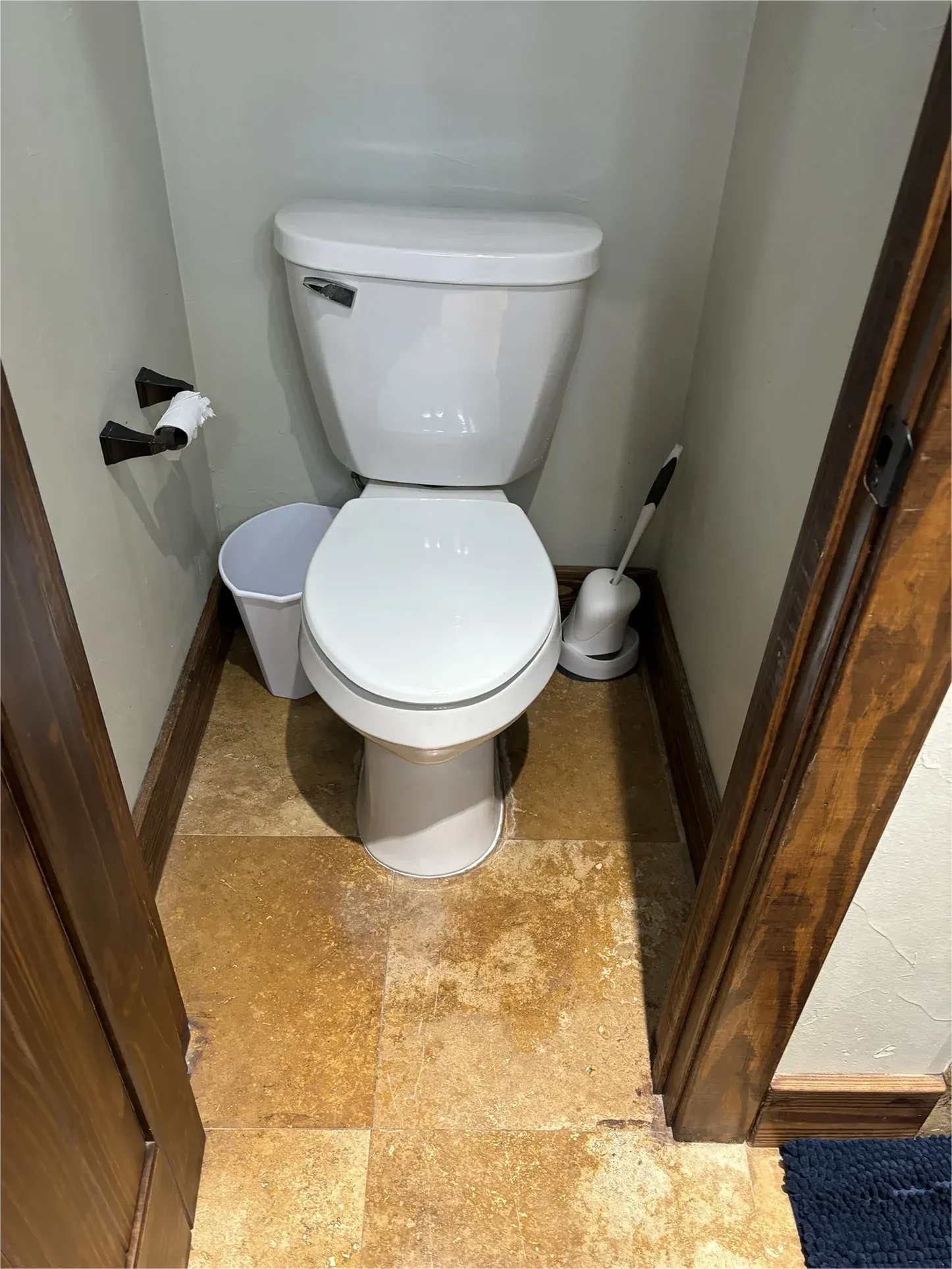 A toilet is sitting in a small bathroom next to a trash can.
