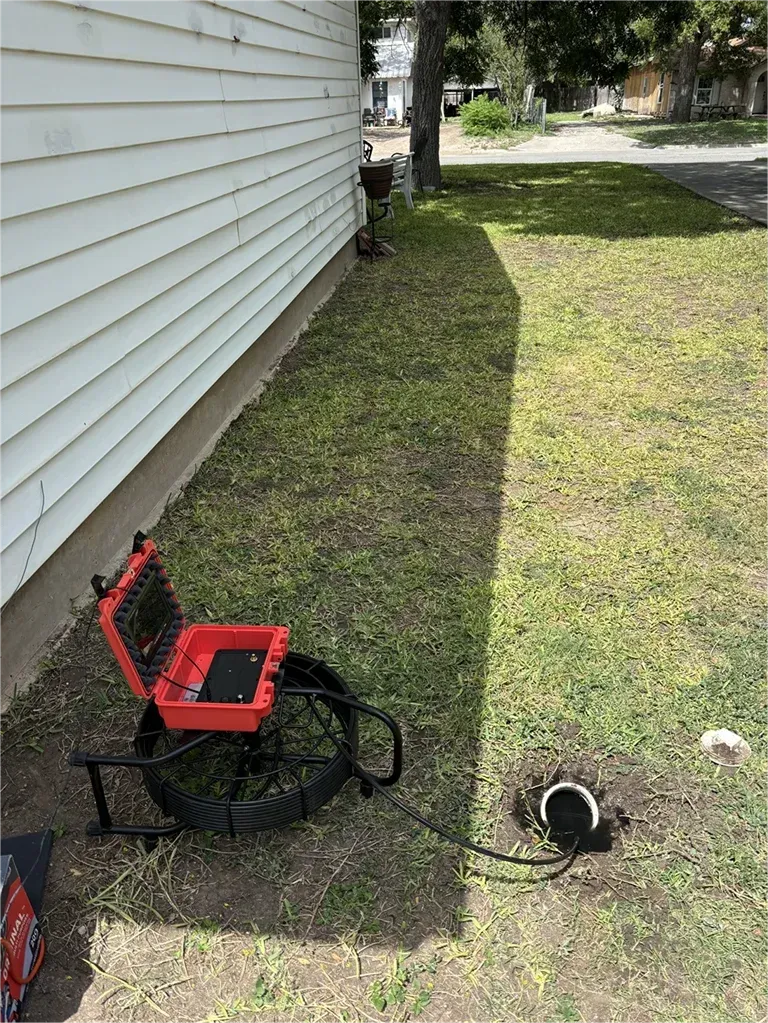 A camera is sitting in the grass next to a house.