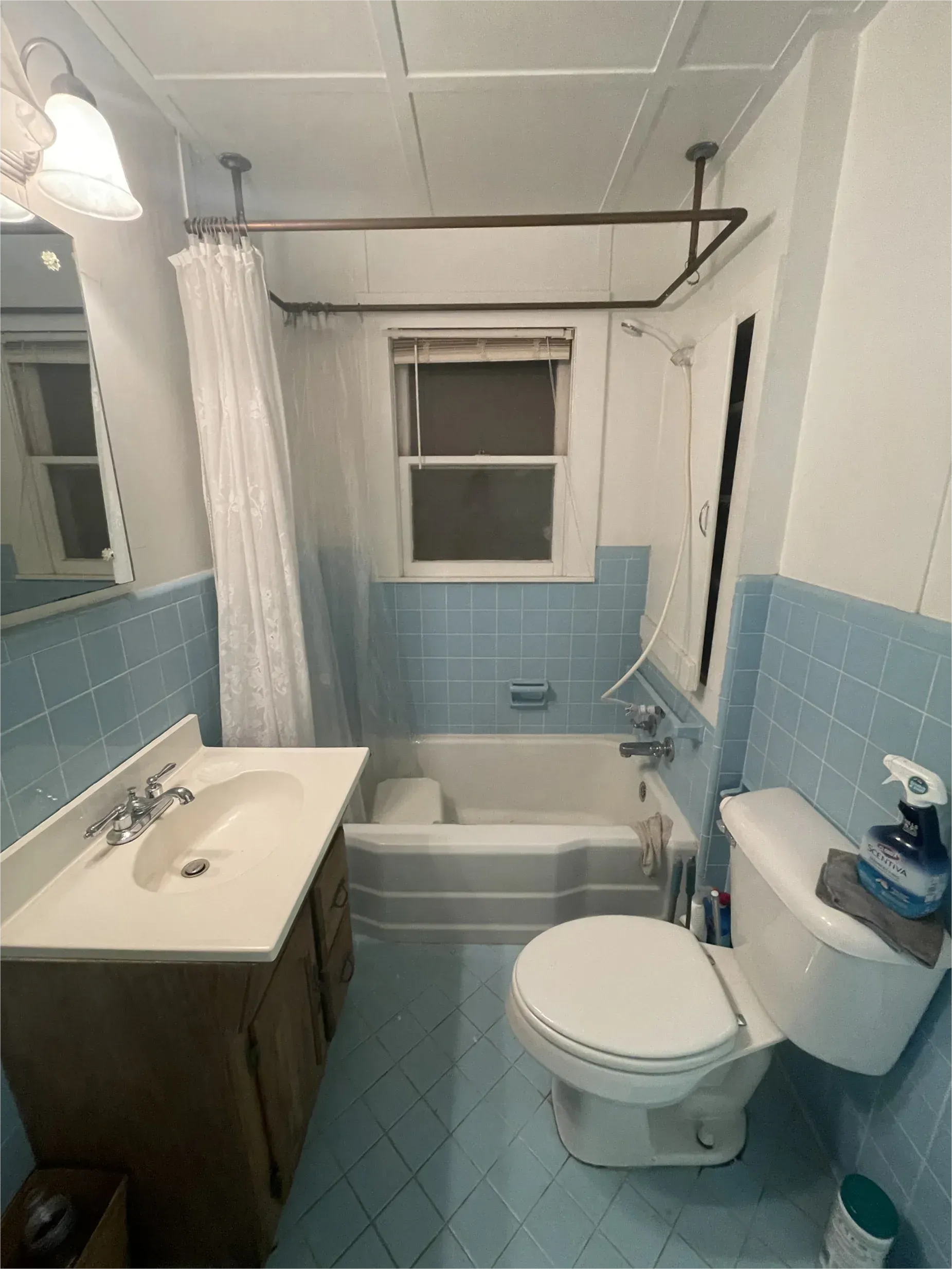 A bathroom with blue tiles , a toilet , sink and bathtub.