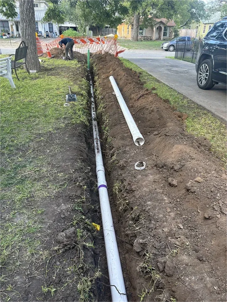 A man is digging a hole in the ground to install a pipe.