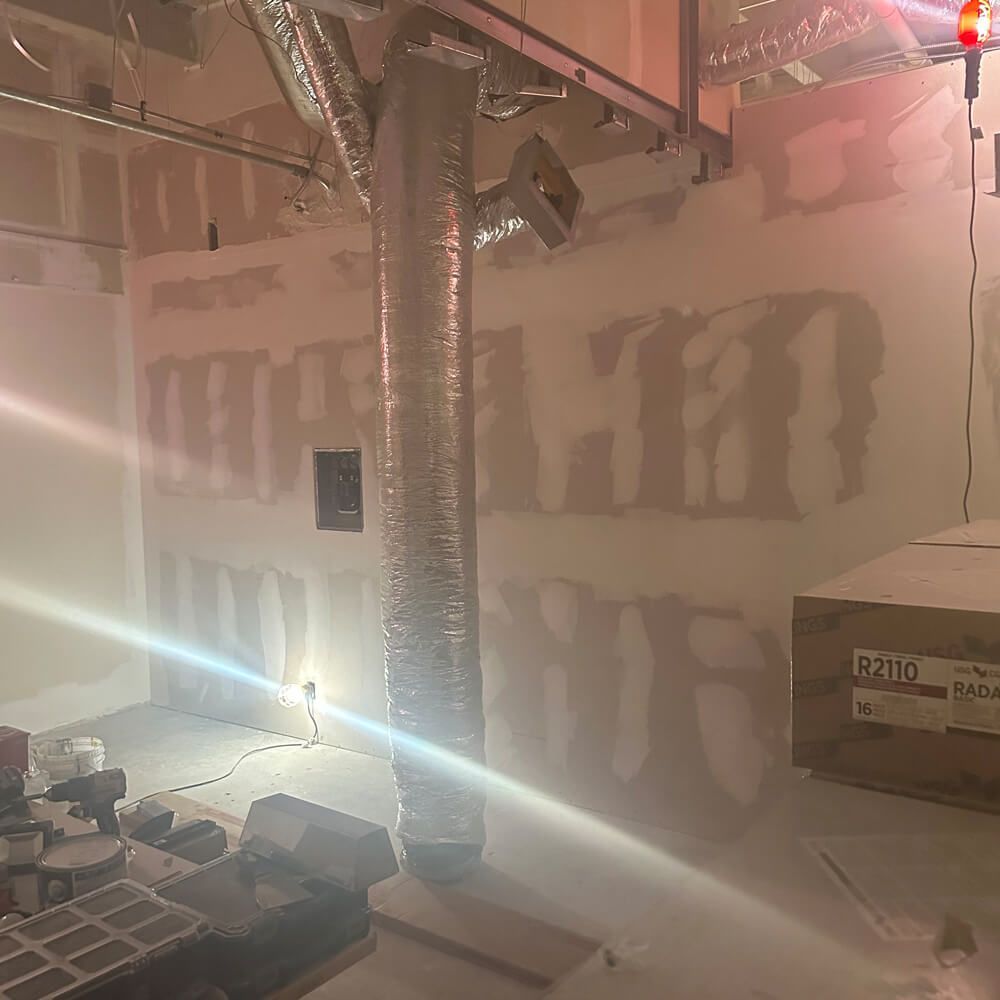 A yellow excavator is working on a construction site in front of a building under construction.