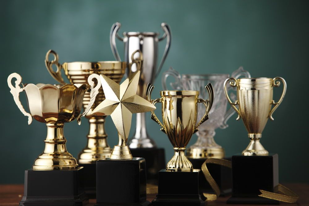 A Group Of Trophies Are Sitting On A Wooden Table — Gala Trophies  In Wollongong, NSW 