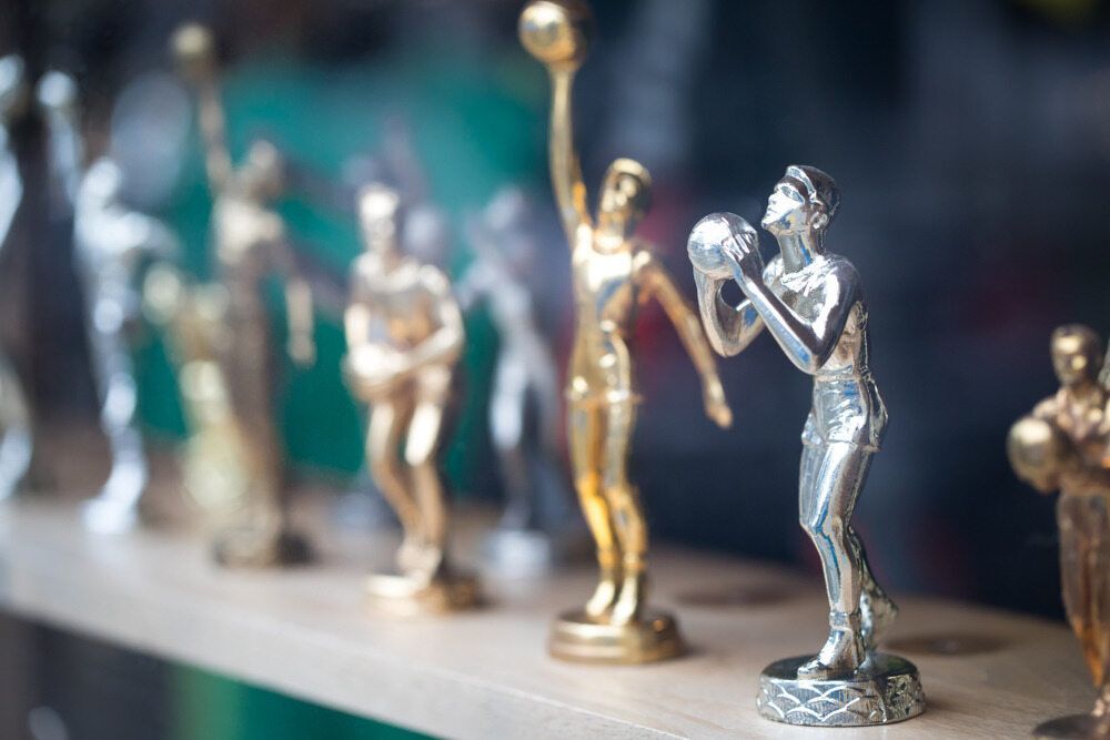 A Row Of Trophies Sitting On Top Of A Wooden Shelf — Gala Trophies  In Wollongong, NSW 