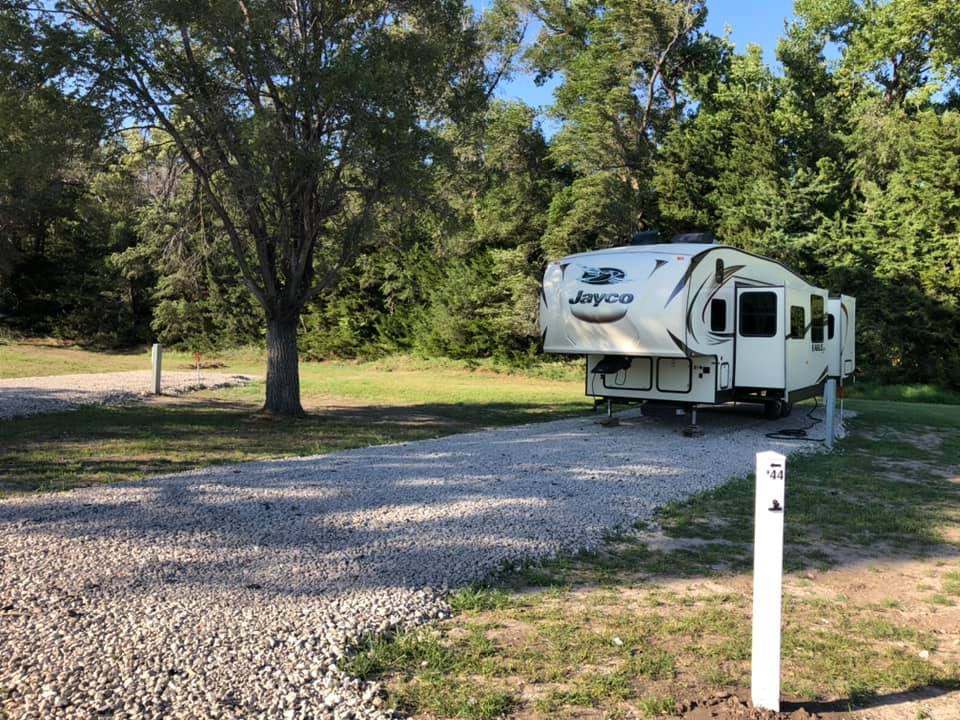 Camper parked on gravel back in at Creek Side Resort in Hays, KS
