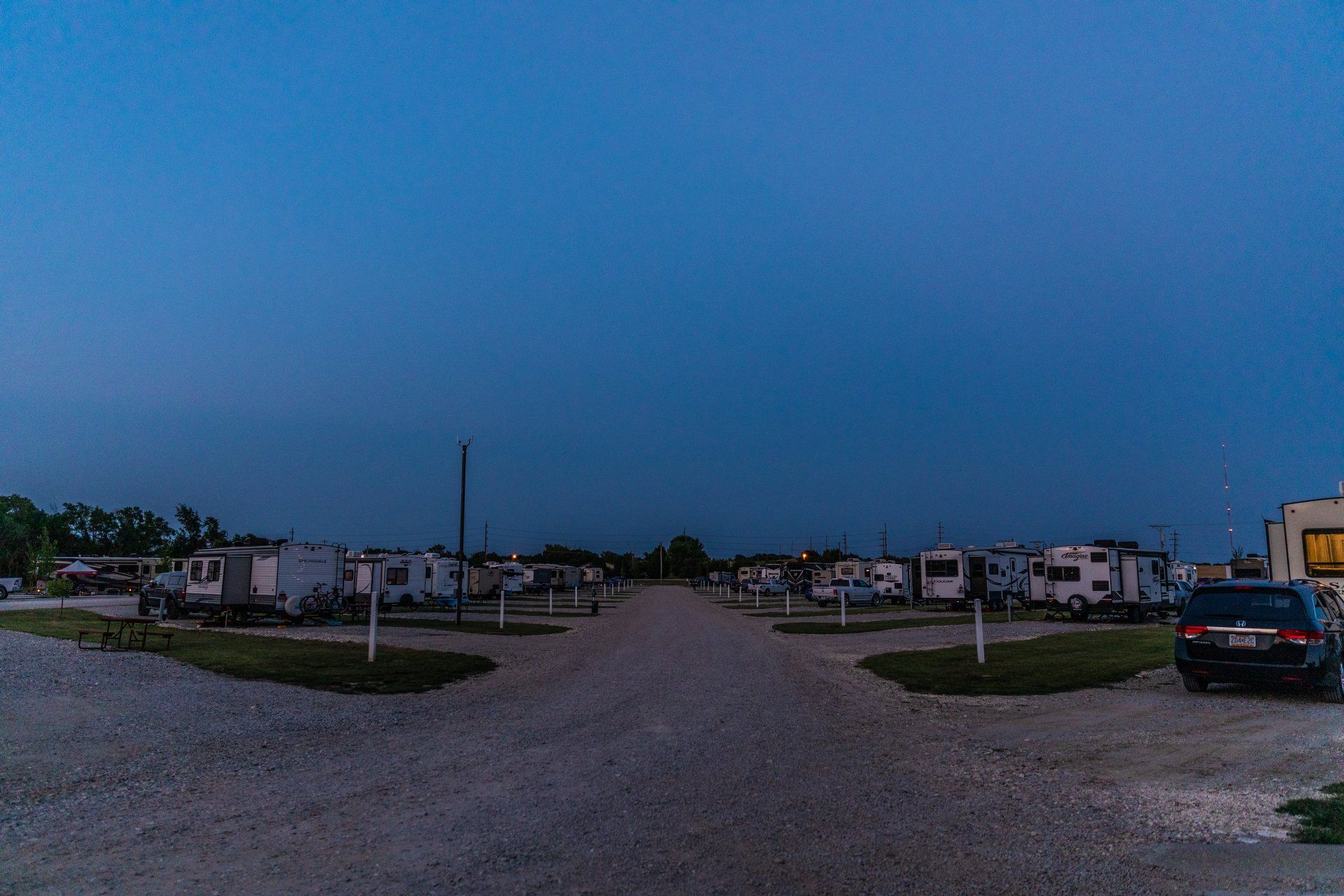 RVs and campers parked in gravel pull through sites at Creek Side Resort in Hays, KS