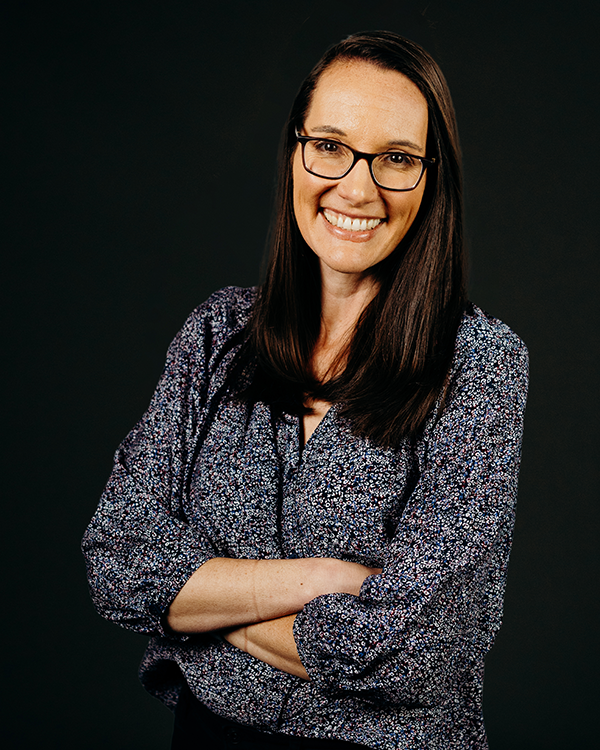 Woman in patterned top smiles at the camera.