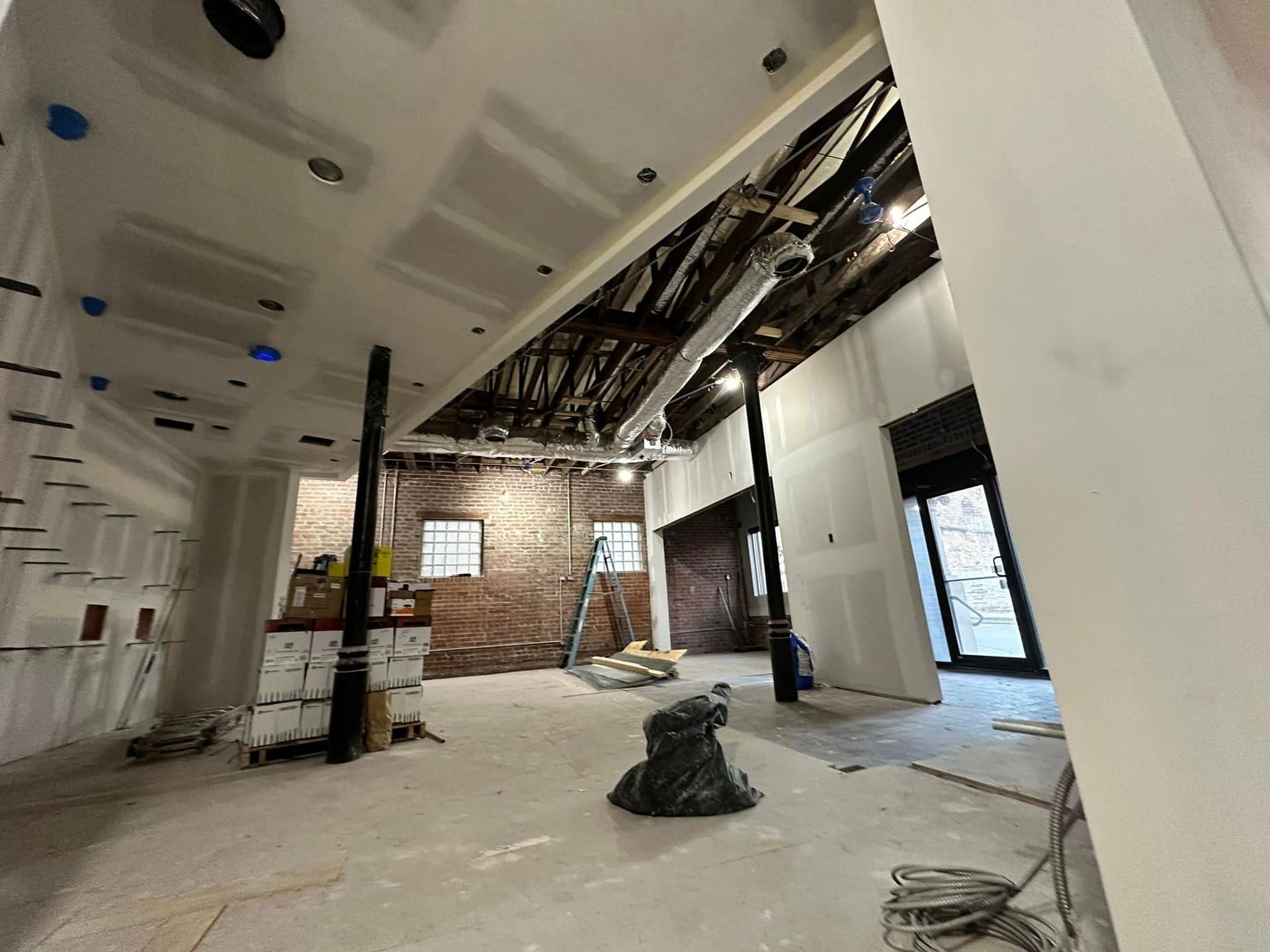A large empty room with a brick wall and a vacuum cleaner on the floor.