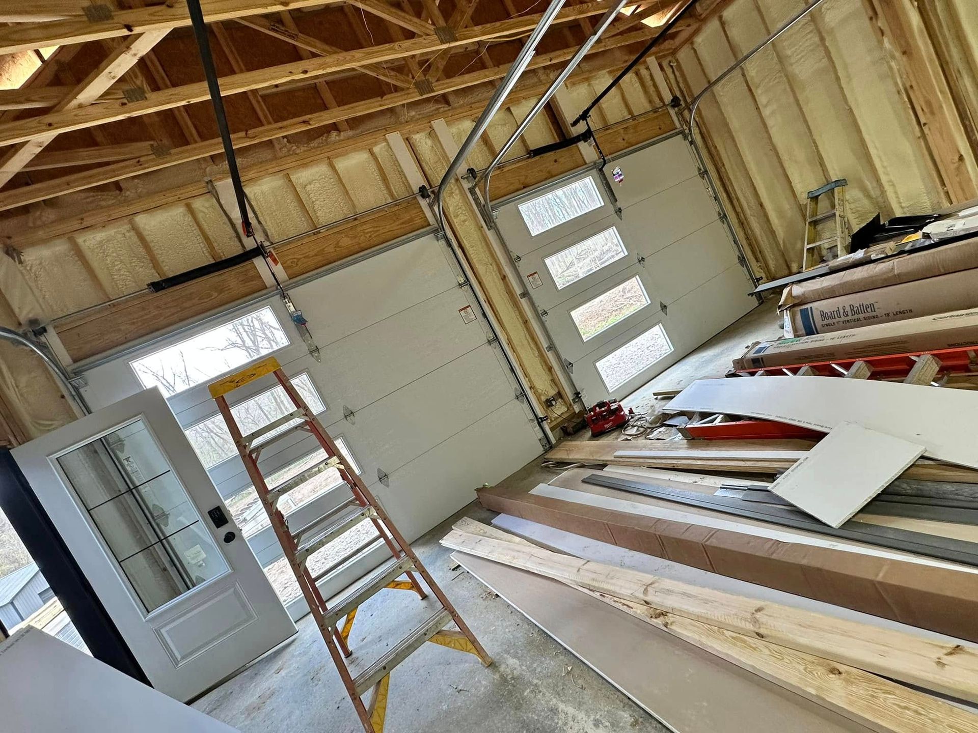 A ladder is sitting in a garage next to a garage door.
