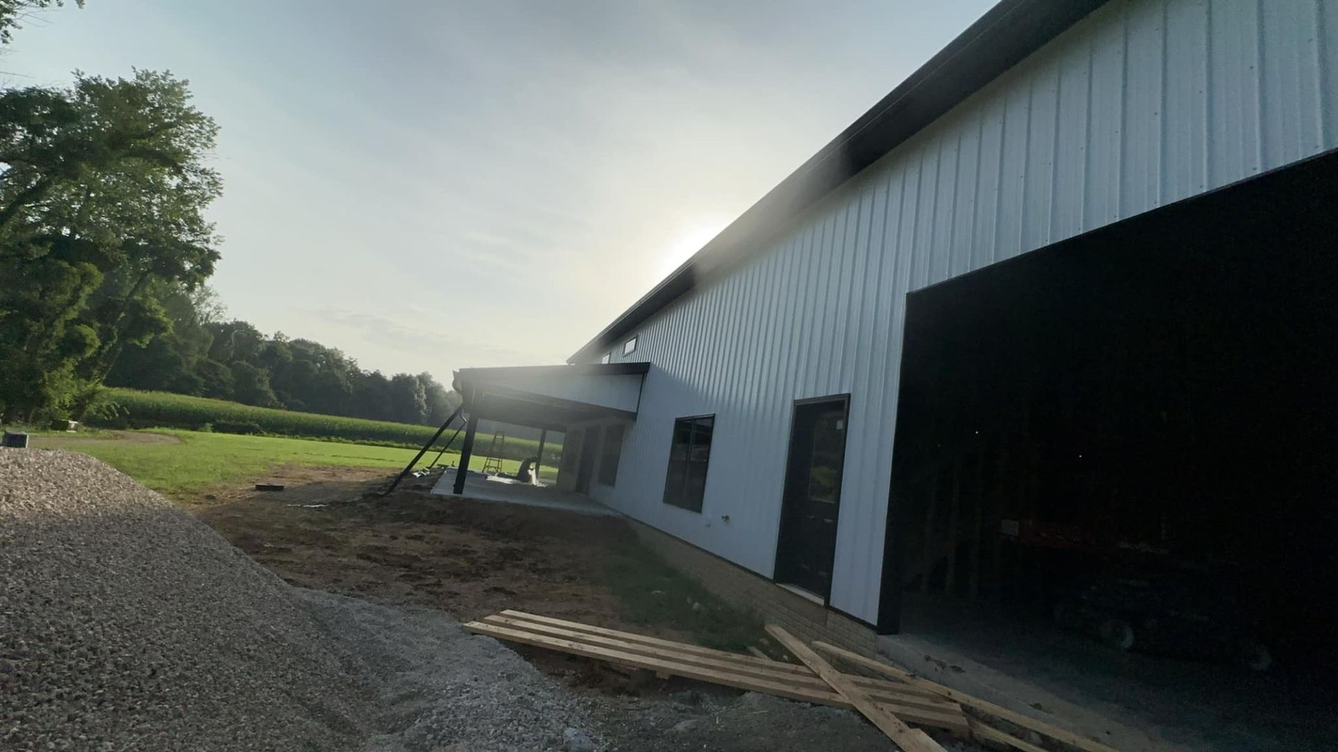 A large white building with a black door is sitting in the middle of a field.